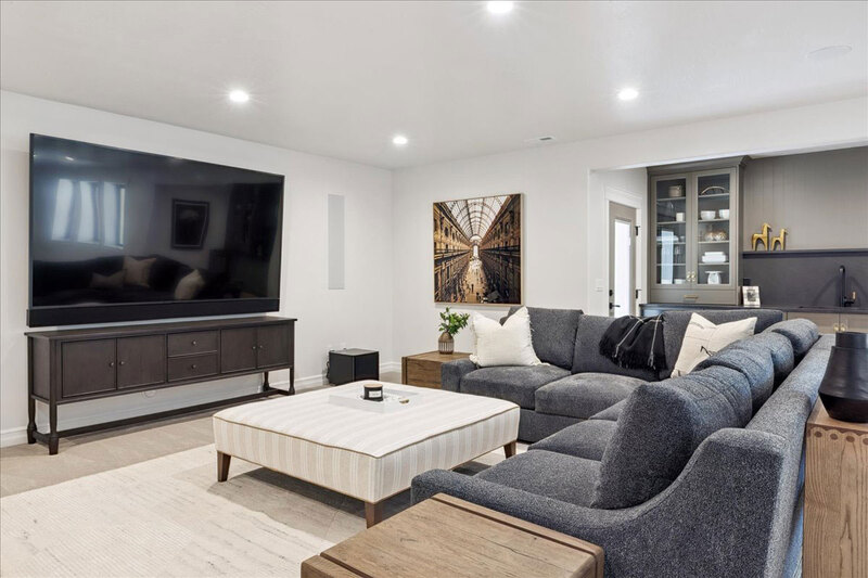Down to Earth Projects<br>Symphony Homes Parade Ninth + North Design - Down to Earth Projects<br>Symphony Homes Parade Ninth + North Design - basement family room with gray sofa and large tv